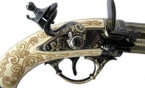 Closeup of tlintlock mechanism and stock on ornate flintlock pistol.